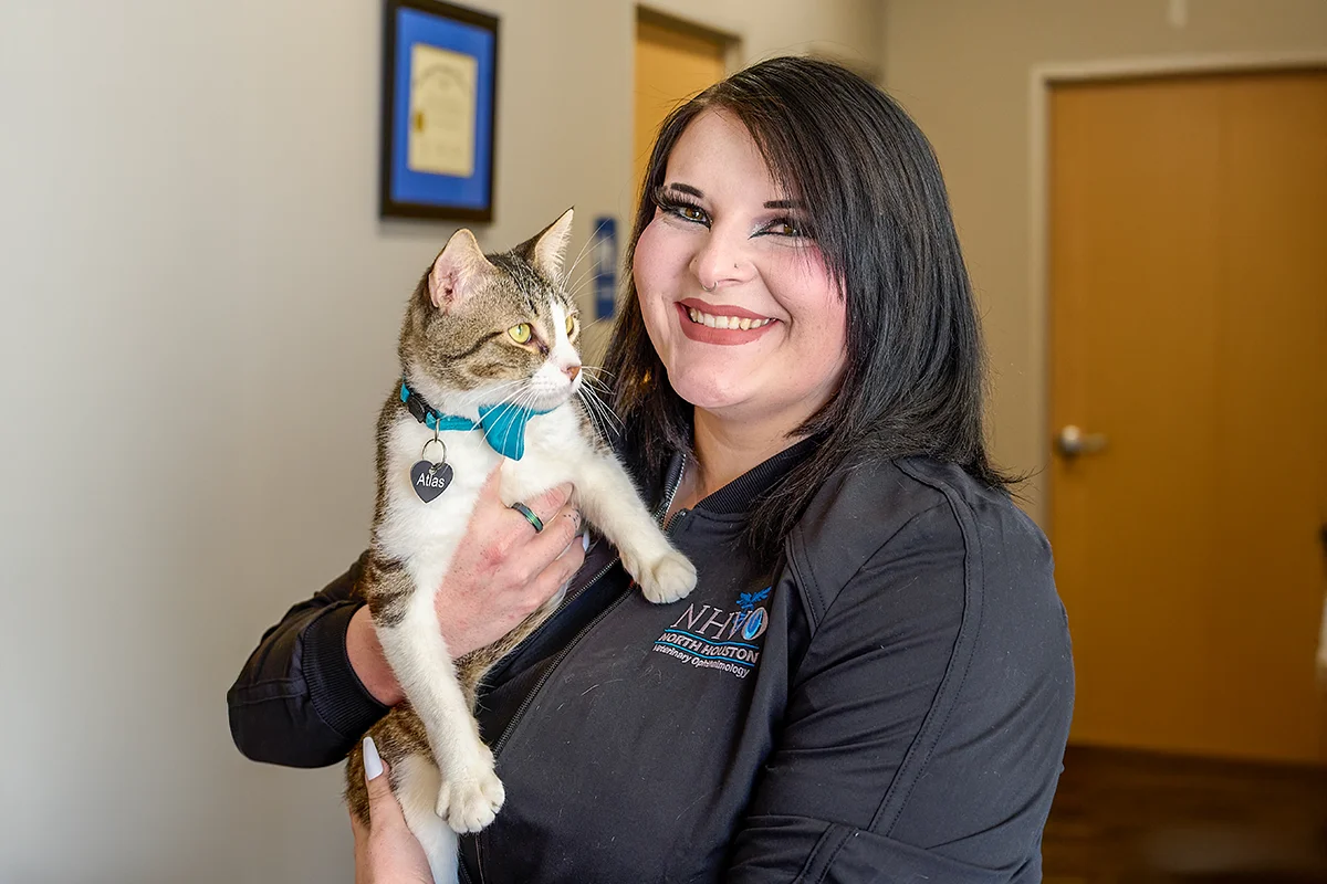 A smiling veterinary staff member holding a cat named Atlas.